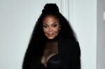 Janet Jackson posando com figurino preto