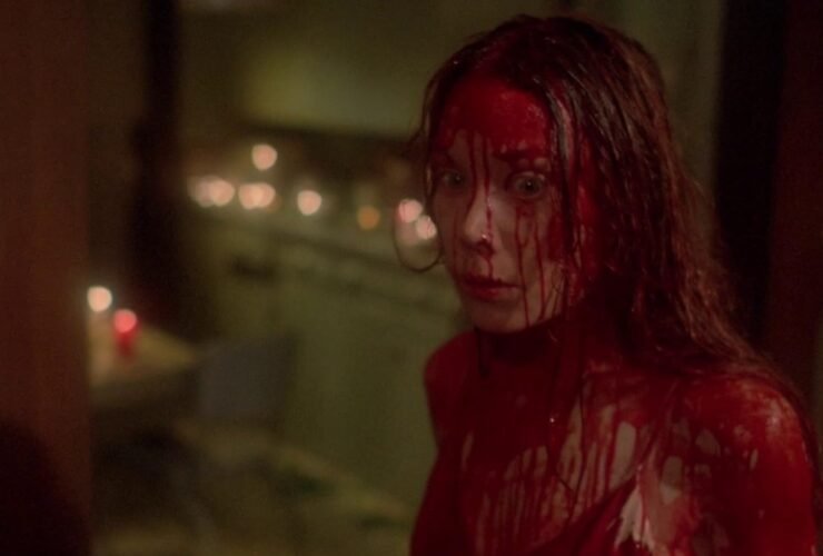 Personagem "Carrie", uma mulher loira, dentro de uma casa com olhar assustado enquanto está coberta de sangue. Crédito: IMDb