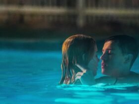 Em uma piscina, uma mulher e um homem estão abraçados e com rostos próximos.