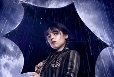 A personagem Wandinha, segura um guarda chuva preto em uma tempestade. O ângulo da imagem é de baixo para cima, então é possível ver o céu tempestuoso ao fundo.