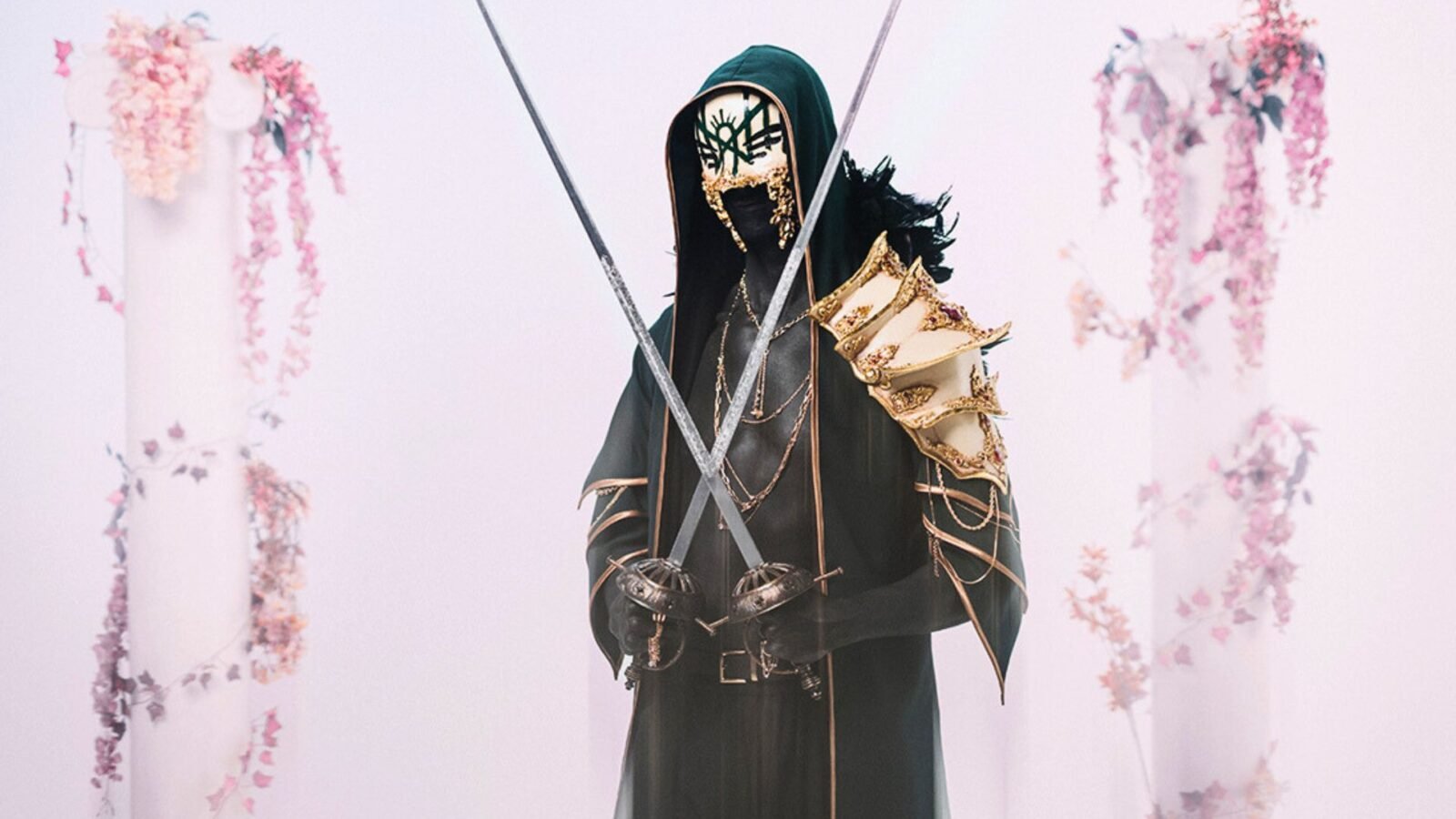 A foto mostra Vessel, líder da banda de rock  e metal Sleep Token. Ele esconde seu rosto com uma máscara na cor branca e um capuz preto. 