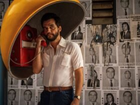 O ator Wagner Moura aparece usando um telefone público em foto de divulgação do filme O Agente Secreto