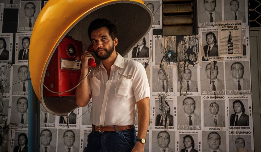 O ator Wagner Moura aparece usando um telefone público em foto de divulgação do filme O Agente Secreto