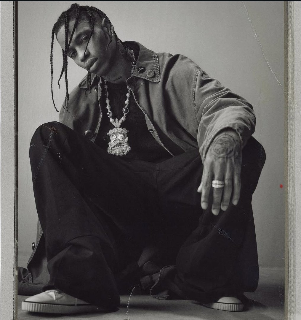 O Rapper Travis Scott, atração do festival The Town 2025, posa para foto. O artista é um jovem homem negro com tranças no cabelo. Ele possui uma tatuagem na mão esquerda e veste roupas largas.