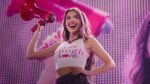 Olivia rodrigo sorri enquanto segura um megafone durante um show