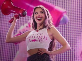 Olivia rodrigo sorri enquanto segura um megafone durante um show