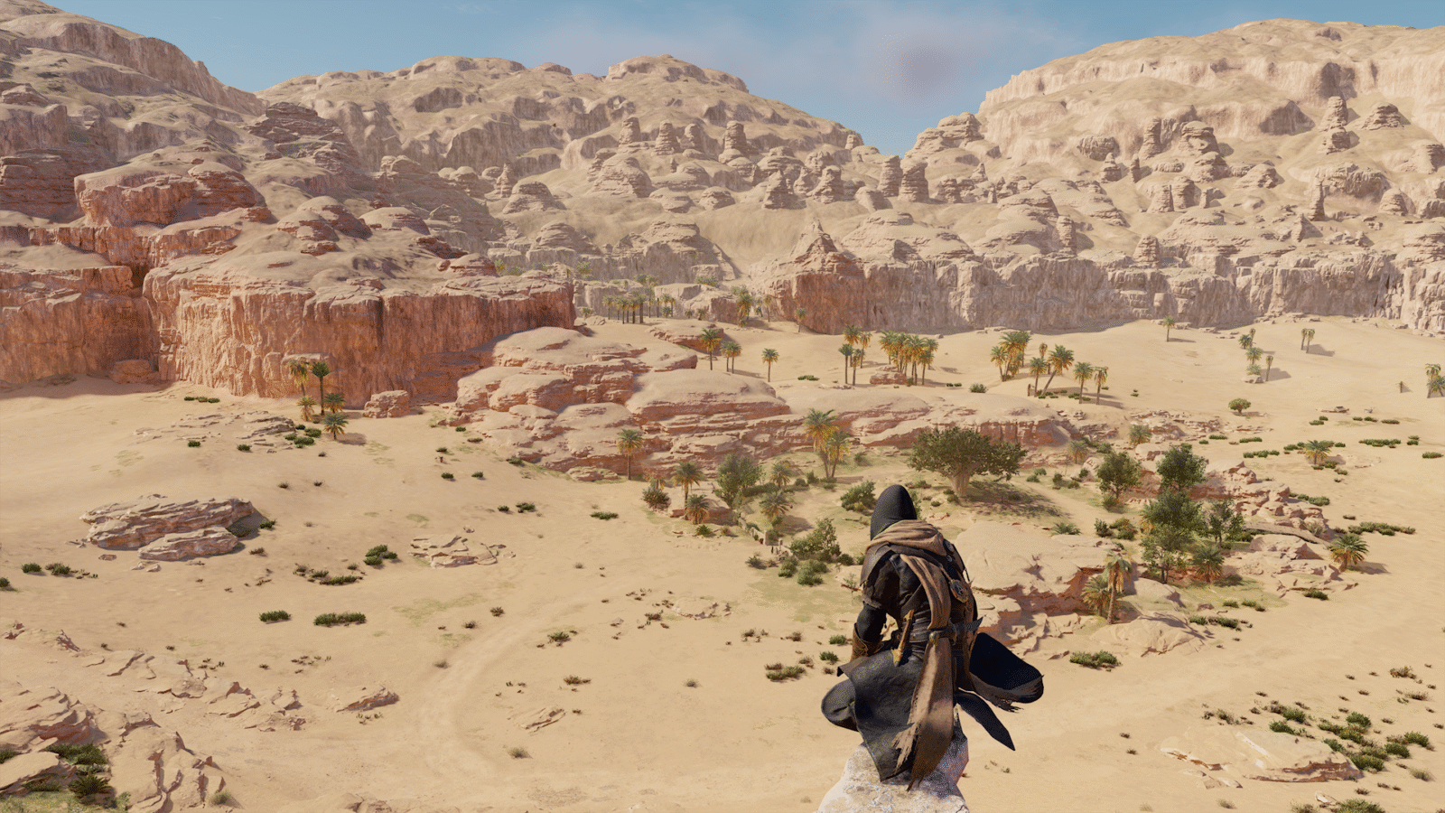 Basim, o protagonista de Assassin's Creed Mirage, está em um ponto alto em uma vasta paisagem desértica com grandes formações rochosas e algumas palmeiras. Ele veste suas vestes escuras e está de costas, contemplando a vista.