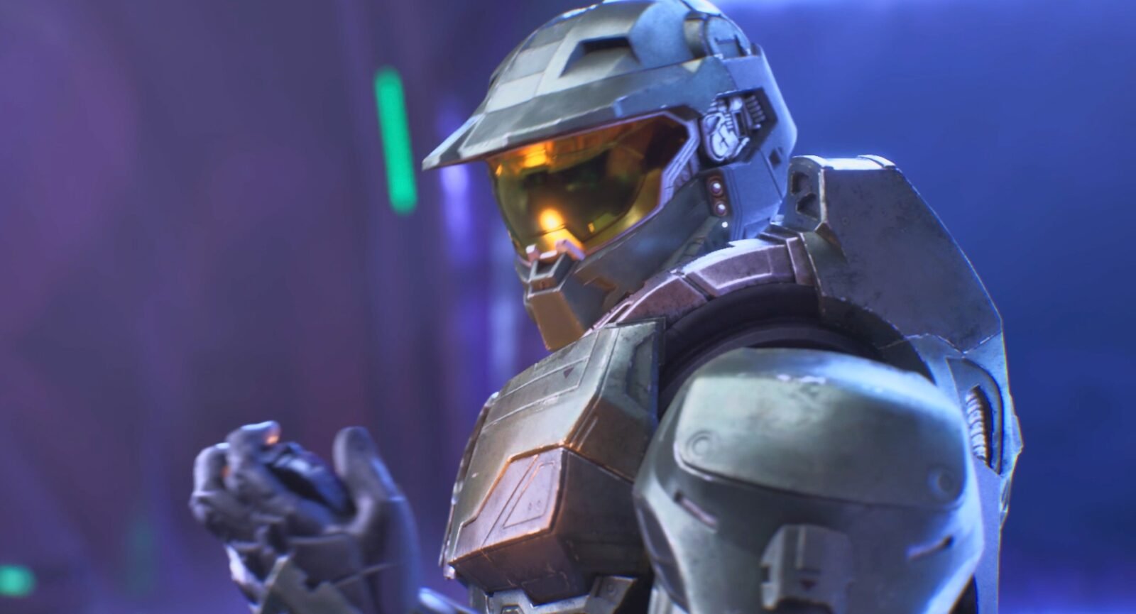 Master Chief de perfil, vestindo sua icônica armadura verde e visor dourado. Ele está segurando e olhando para um pequeno dispositivo escuro nas mãos enluvadas. O fundo é desfocado, banhado em luzes intensas de tons roxos, azuis e feixes de néon verde