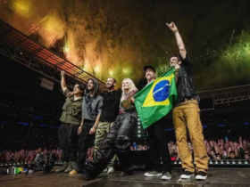 Foto do Linkin Park no palco do Allianz Parque em 2024. A banda posa com a bandeira do Brasil diante de uma multidão e fogos de artifício.